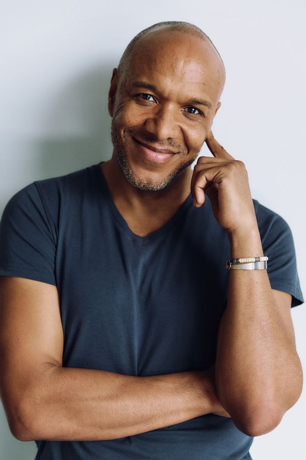 Alfred C. Kemp headshot, charcoal V-neck tee, hand at cheek